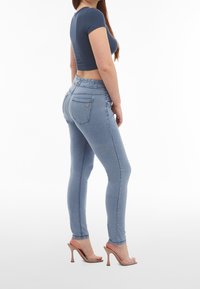 Ljust blå skinny jeans med en stretchmidja, med två bakfickor och eleganta sömmar. Bärs med genomskinliga sandaler och en marinblå crop top.