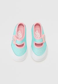 Sapatos de tecido turquesa brilhante com um acabamento rosa, apresentando uma tira ao estilo Mary Jane, sola branca e palmilha com marca.