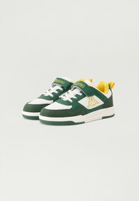 Πράσινα και λευκά αθλητικά παπούτσια με τρυπητή λεπτομέρεια, υφασμάτινες πράσινες λεπτομέρειες, κίτρινο λογότυπο στη γλώσσα και στην πίσω αγκράφα. Διαθέτουν ιμάντα με κλιπ.