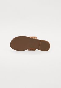 Semelle en caoutchouc marron d'une sandale avec un dessus tissé coloré, comportant des fils multicolores et un design plat, sans accents visibles.