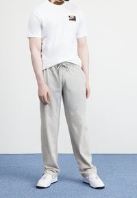 Weißes Nike T-Shirt mit Logo, graue Sweathosen mit Kordelzug und weiße Sneakers. Schlichte Stoffqualität, lockere Passform, lässiger Stil, minimalistisches Design.