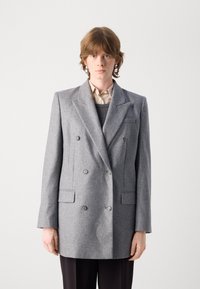 Grijze dubbele blazer van textuurstof, met twee voorzakken, gekartelde revers en metalen knopen. Gestructureerde silhouet.