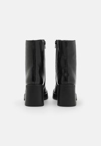 Black leather ankle boots with a square toe and chunky heel. Features a zip closure at the back for easy wear. Smooth texture.