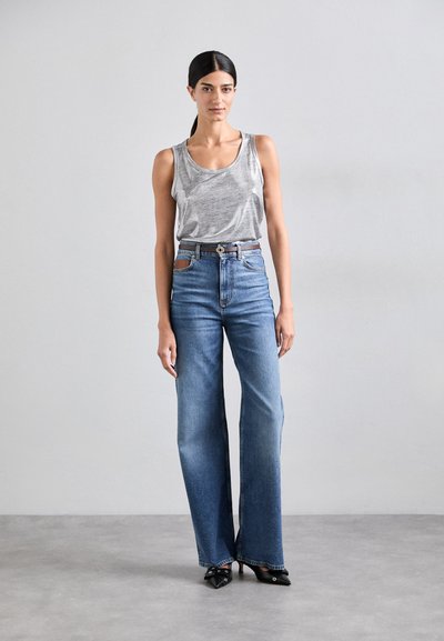 Top gris sin mangas, jeans anchos de tiro alto en azul, cinturón marrón con hebilla de metal, tacones negros de punta, tejido suave y textura clásica de denim.