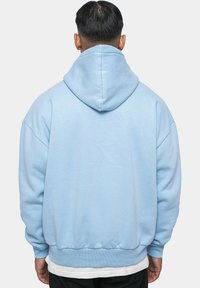 Helle blaue Kapuzen-Sweatshirt mit lockerer Passform, gerippten Bündchen und Saum. Das Design verfügt über eine große Kapuze und ist aus weichem, strukturiertem Stoff gefertigt.