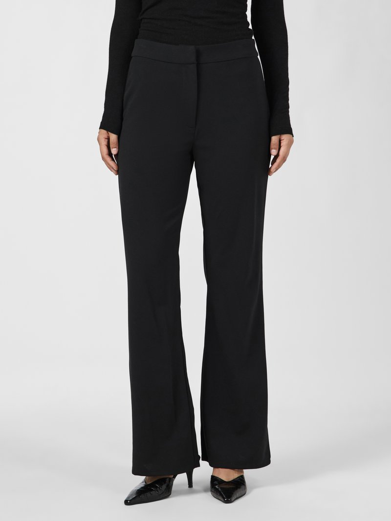 Pantaloni neri con una vestibilità su misura, gambe dritte, tasche frontali e una texture liscia, abbinati a tacchi neri a punta.