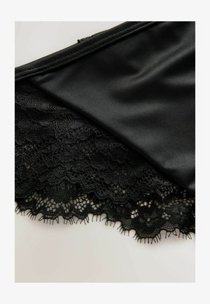 Mustalane, millel on sile satiinist ülemine osa ja keerukad pitsiisiku äärised lillemustriga ning lainelised servad, luues kihilise tekstuuri.