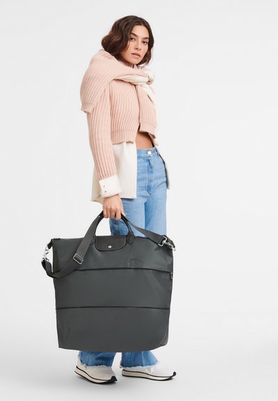 Gray nylon tote bag with double handles, silver hardware, and front zip pocket. Textured accents on the top and a spacious design.