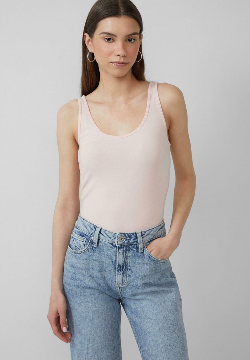 Lichtroze tanktop met een lage ronde halslijn, gecombineerd met lichtblauwe hoge taille rechte jeans, wat een casual outfit laat zien.