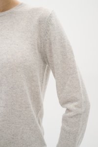 Light gray knitted sweater with a round neckline, featuring a soft texture and fitted sleeves, showcasing subtle variations in color.