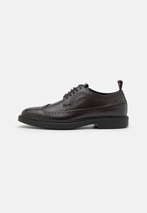 Chaussure habillée à bout fleuri en cuir marron avec détails perforés, bout arrondi, design à lacets et semelle en caoutchouc noire avec une languette de traction.