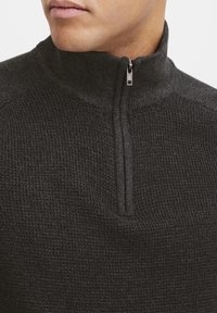 Pull-over demi-fermeture éclair gris foncé en tissu tricot côtelé à finition texturée, doté d'un col montant et d'une fermeture éclair discrète.