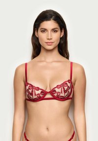 Rød broderet bh med gennemsigtigt stof, der har et blomsterdesign og satinremme. Skålene er struktureret med en vandret undertråd.