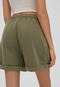 Bermudas verde oliva hechas de una tela suave, con un corte relajado, una cintura elástica y bajos enrollados para un look informal.