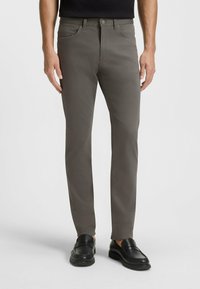 Szare slim-fit spodnie wykonane z mieszanki bawełny, z klasycznym pięciopocketowym krojem i zapięciem na guzik, w połączeniu z czarnymi loafersami.