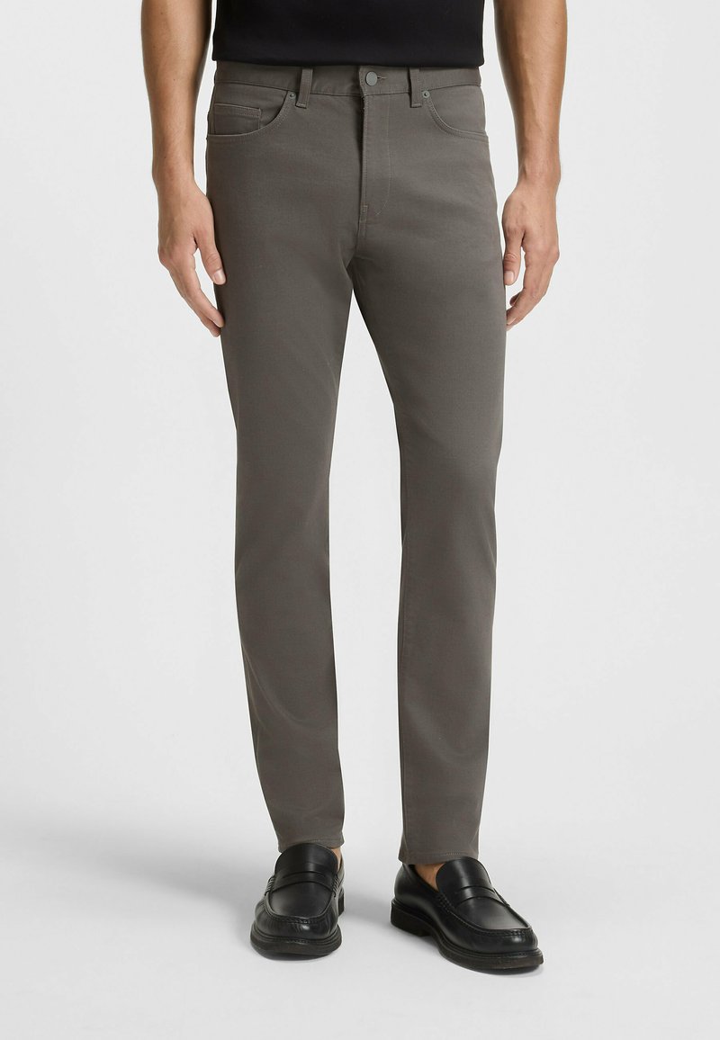 Szare slim-fit spodnie wykonane z mieszanki bawełny, z klasycznym pięciopocketowym krojem i zapięciem na guzik, w połączeniu z czarnymi loafersami.