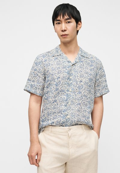 Chemise à manches courtes en tissu léger avec un motif floral bleu sur fond crème. Dotée d'un col classique et d'une patte de boutonnage.