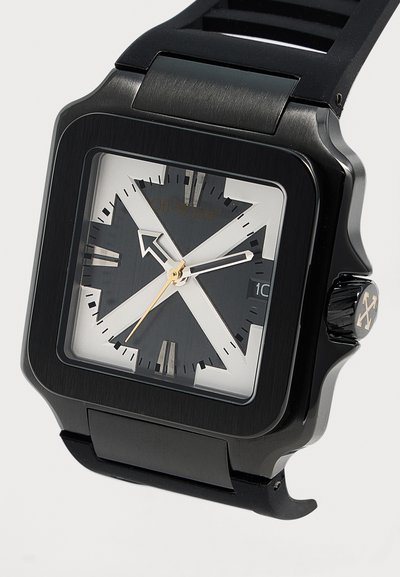Montre-bracelet carrée noire avec des index angulaires blancs, une fenêtre de date à trois heures et un bracelet en silicone noir.