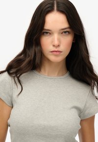 Camiseta gris ajustada con cuello redondo y mangas cortas. Fabricada en una tela suave con una sutil textura de canalé.