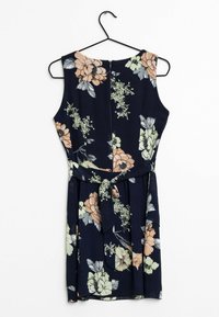 Robe florale avec une base marine, présentant de grandes fleurs pêches et vertes claires, sans manches, et une ceinture en tissu à la taille.