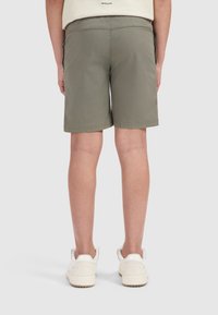 Olijfgroene shorts van lichtgewicht stof met een rechte snit, voorzien van een eenvoudige zoom en zijzakken, gezien van achteren.