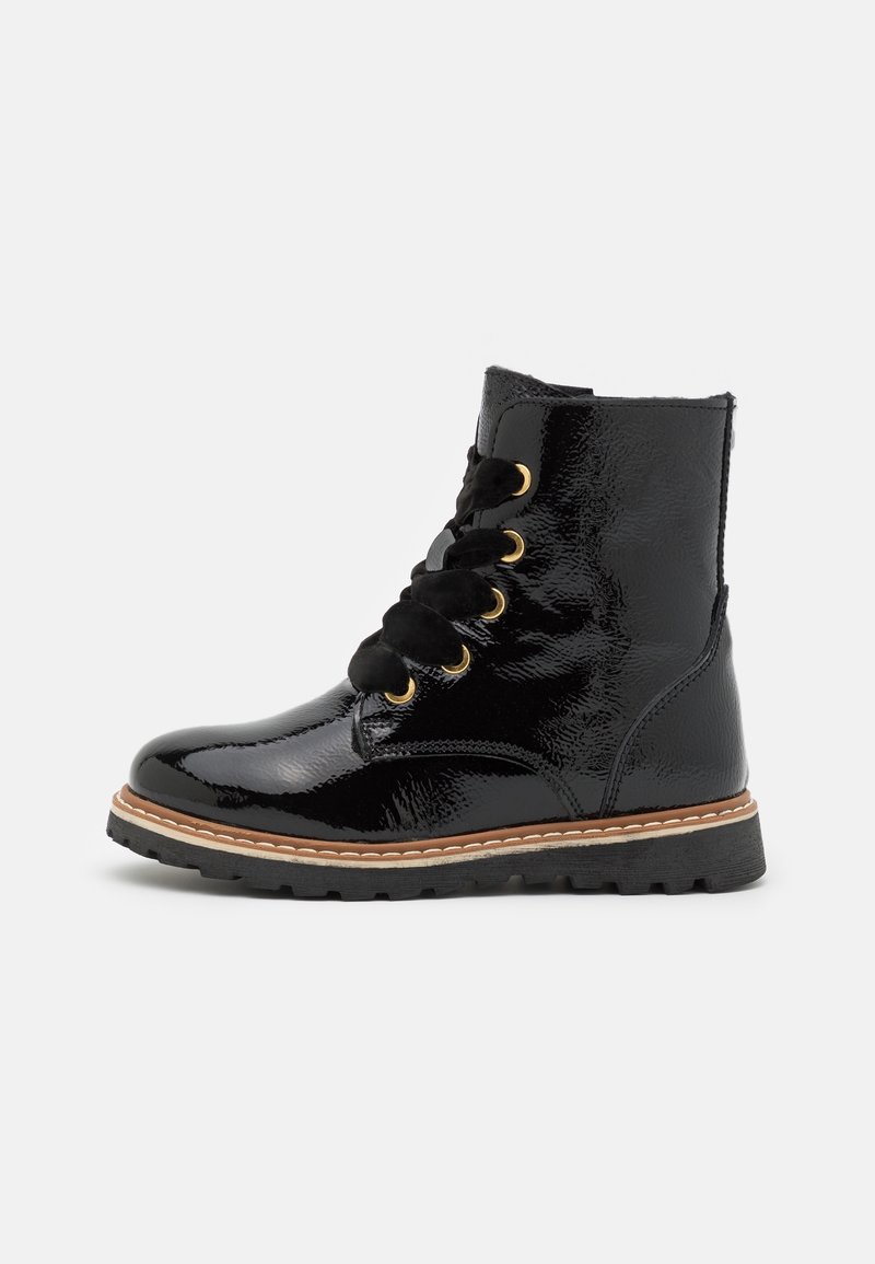 Bottine noire en cuir verni brillant avec une semelle noire épaisse, surpiqûres marron, œillets dorés et larges lacets noirs.