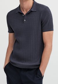 Navy short-sleeve polo shirt with a textured ribbed design, comfortable fit, and button placket at the collar.
