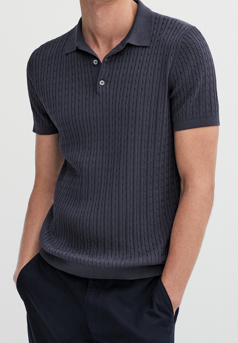 Navy short-sleeve polo shirt with a textured ribbed design, comfortable fit, and button placket at the collar.