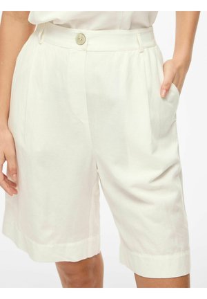 Vrouw draagt witte shorts met hoge taille tot op de knie met knoopsluiting, zijzakken en lichte plooidetail.
