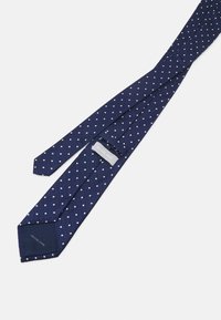 Marineblaue Krawatte mit strukturiertem Muster und kleinen weißen Punkten. Verfügt über eine ausgeprägte, einfarbige marineblaue Spitze. Markenlabel: Michael Kors.