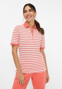 Polo a righe in corallo e bianco, maniche corte, con colletto corallo uniforme e cinque piccoli bottoni, realizzato in un tessuto morbido.