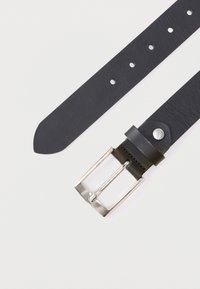 Μαύρη δερμάτινη ζώνη με λεία υφή, που διαθέτει πολλαπλές τρύπες και ασημένια μεταλλική αγκράφα για προσαρμοζόμενη εφαρμογή.