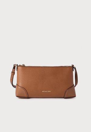 Pochette Michael Kors en cuir marron avec fermeture éclair dorée et bandoulière réglable sur fond uni.