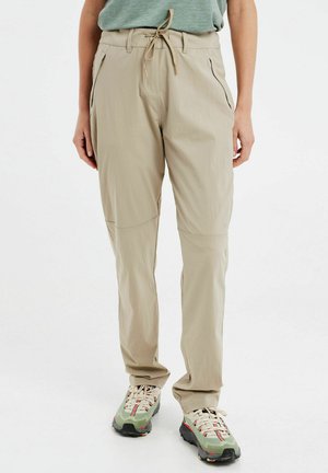 Pantaloni cargo beige leggeri con vita elasticizzata, tasche con zip e una vestibilità comoda, abbinati a calzature verdi texturizzate.