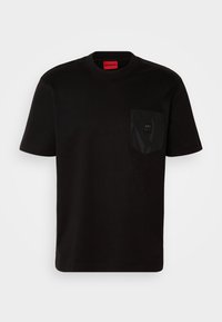 T-shirt noir à manches courtes avec col rond et poche poitrine texturée avec un petit patch logo sur fond blanc uni.