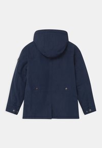 Giacca blu navy con cappuccio, caratterizzata da un taglio dritto, dettagli con chiusura a scatto, aperture posteriori e materiale liscio e resistente all'acqua.