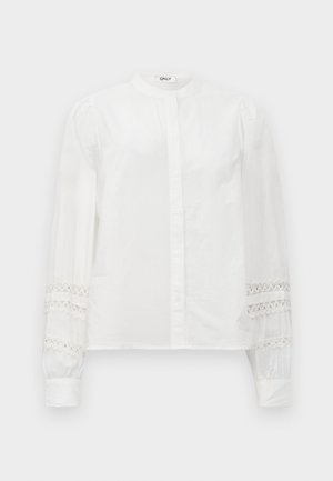 Cămașă albă cu guler înalt, mâneci lungi care prezintă accente de dantelă la manșete și un finisaj neted din bumbac.