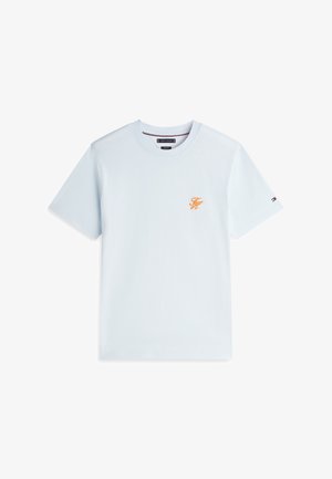 Jasnoniebieski t-shirt z krótkim rękawem i okrągłym dekoltem, z małym pomarańczowym logo "TH" na piersi oraz drobnym detalem w formie flagi na lewym rękawie.