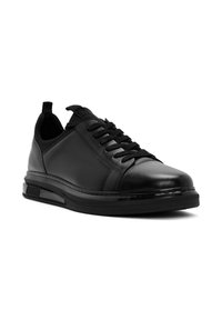 Sneaker in pelle nera con accenti testurizzati, lacci piatti e suola imbottita. Presenta un design elegante e una linguetta sul tallone.