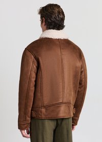 Giacca in shearling marrone con colletto bianco e soffice. Texture trapuntata su una vestibilità rilassata, con dettagli laterali e finitura liscia.