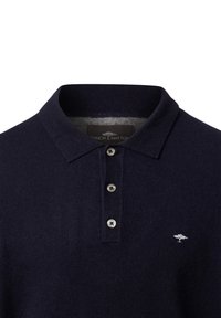 Marineblaue Poloshirt aus strukturiertem Stoff, kurzer Kragen, drei Knöpfe und ein kleines weißes gesticktes Logo auf der linken Brust.