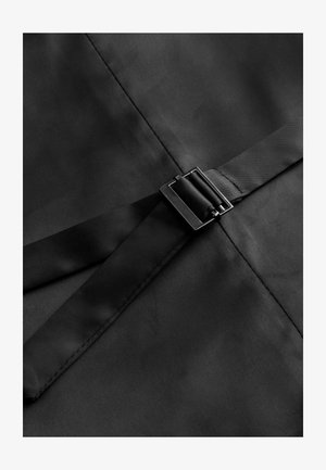 Tessuto nero con una superficie liscia, caratterizzato da una larga fascia al centro fissata da una fibbia quadrata in metallo nero.