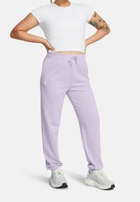 Ljuslila sweatpants med dragsko i midjan, ankelmanchetter och en liten logotyp på vänster ben, i kombination med en vit åtsittande t-shirt.