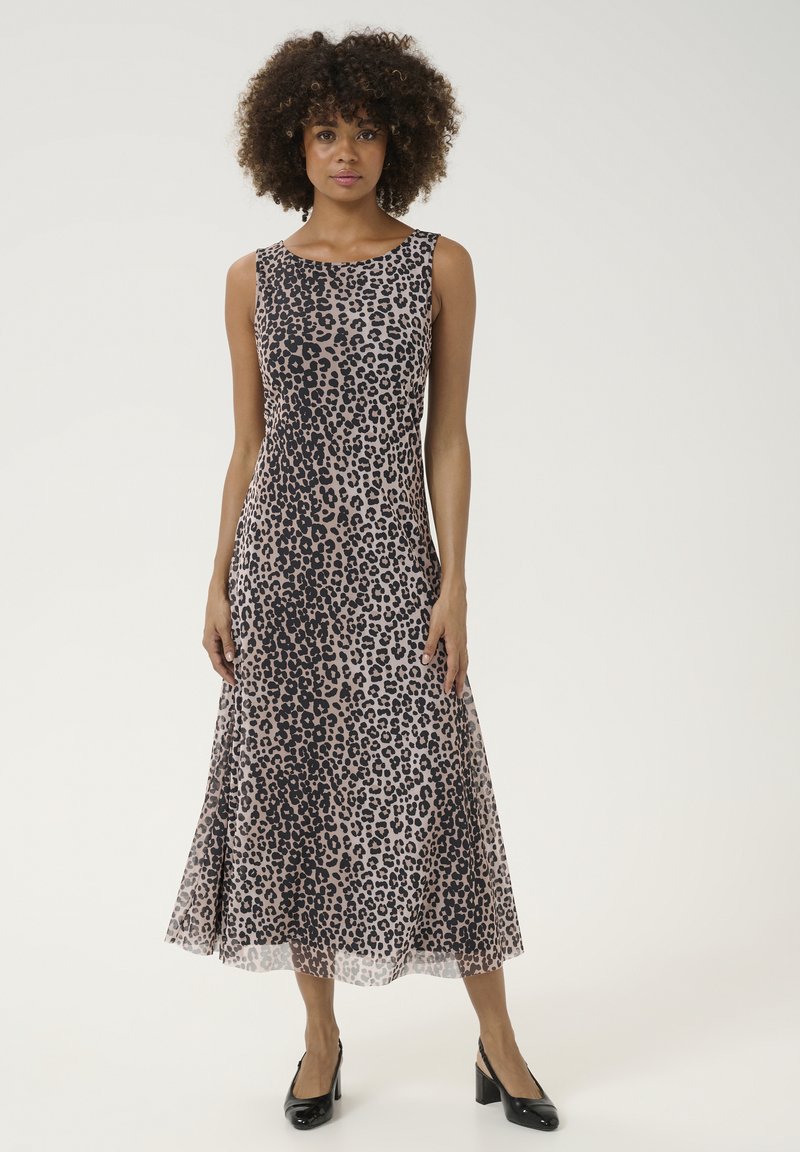Rochie bej fără mâneci cu imprimeu leopard negru, cu o formă A-line fluidă și tiv transparent. Purtați cu pantofi cu toc înalt negri.