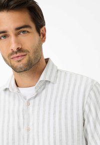 Camicia in lino a righe bianche e grigie con colletto button-down, caratterizzata da un tessuto testurizzato e due bottoni sul fronte.