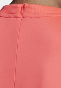 Detail zadní části korálových šatů se smooth materiálem, kulatým výstřihem a decentním zipovým zap ínáním. Jednoduchý design, bez viditelných vzorů.