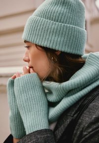 Mint green ribbed knit beanie, scarf, and fingerless gloves. Soft texture, snug fit, and contrasting ribbed pattern detail.