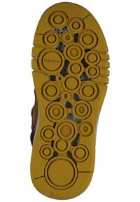 Suola di scarpa in gomma gialla con un motivo circolare, logo in rilievo "GEOX" e numerosi fori di ventilazione per traspirabilità.