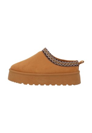 Beige instapper met dikke zool, getextureerd profiel, treklus aan de hiel en een patroonrand om de enkelopening, van opzij gezien.