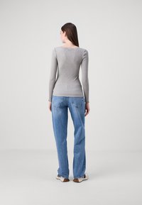Grå langermet ribbe-top kombinert med lyseblå vide jeans. Toppen har en tettsittende design, mens jeansene har en klassisk fem-roms stil.